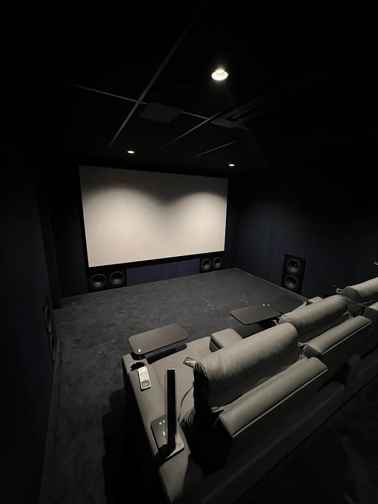 Fotografia de home cinema do acervo Os Especialistas, com poltronas reclináveis, projeção frontal e tratamento acústico escuro.